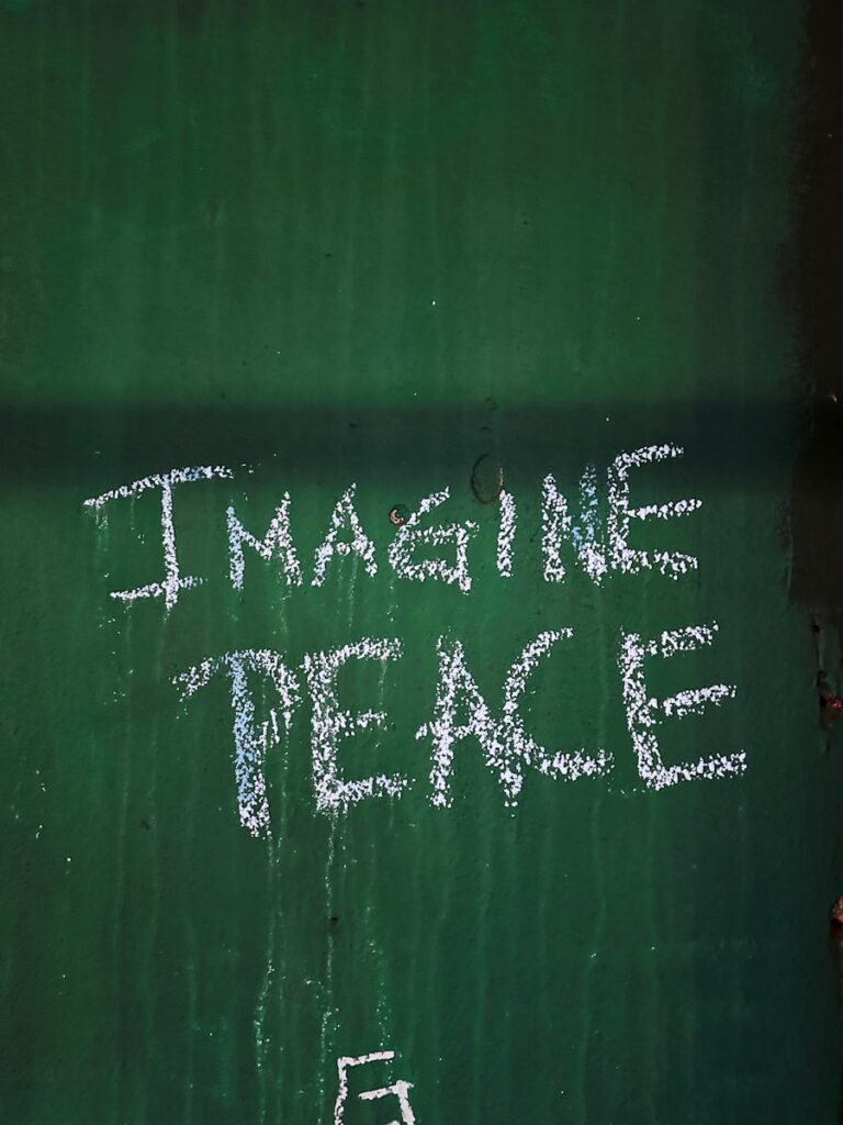 a chalk drawing on a green wall that says imagine peace