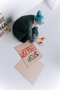 A woman painting anti-fascism signs, preparing for a protest with bold red and black text.