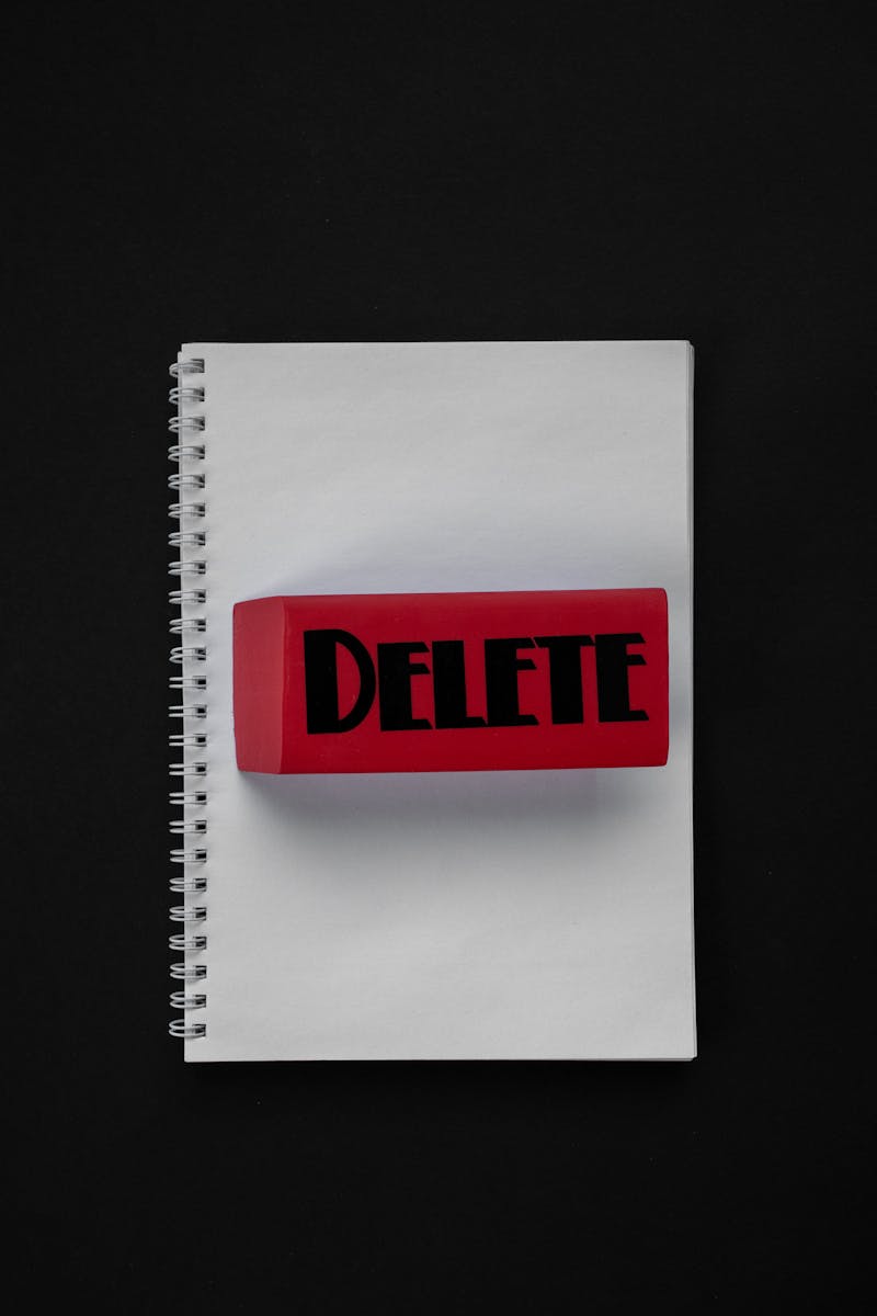 Red block inscribed with 'Delete' on a flat lay spiral notebook over black background.