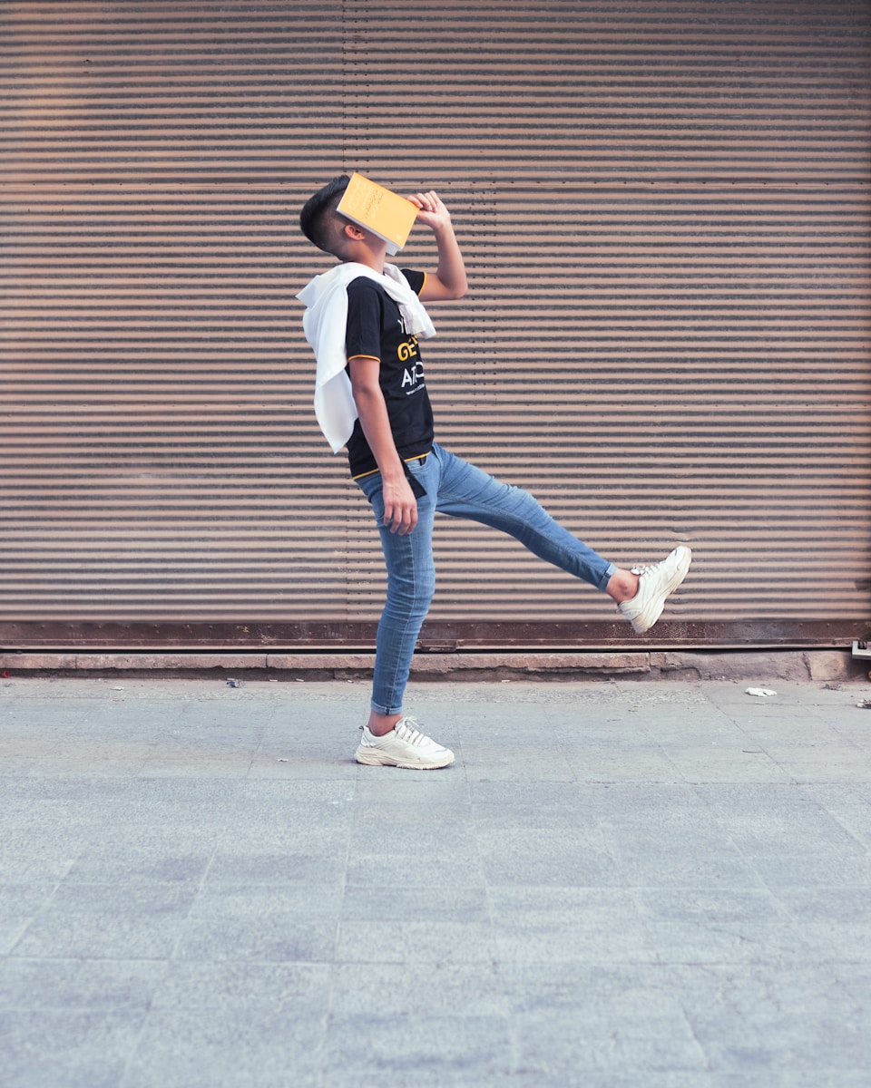 woman in white shirt and blue denim jeans standing on sidewalk during daytime