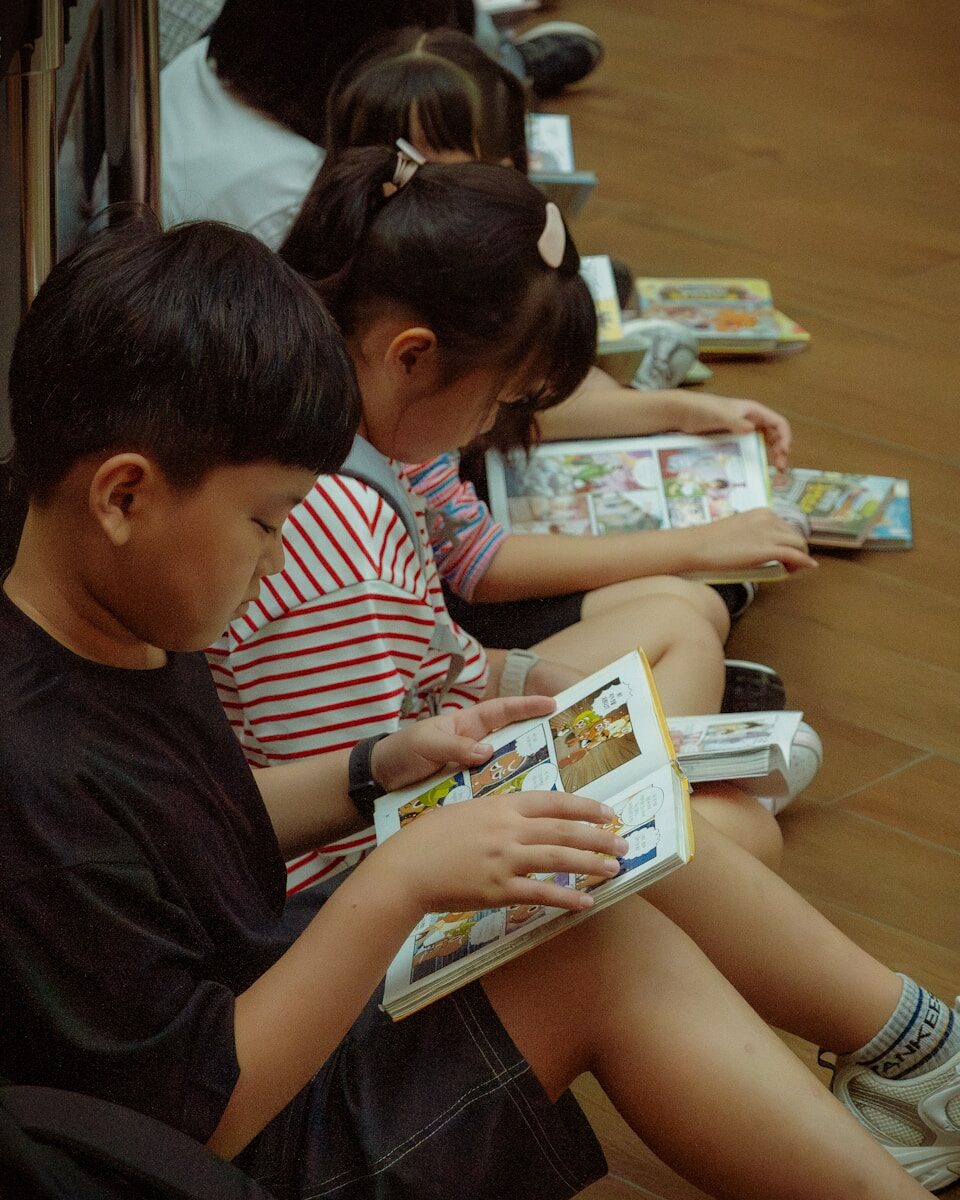Young children quietly read comic books on the floor