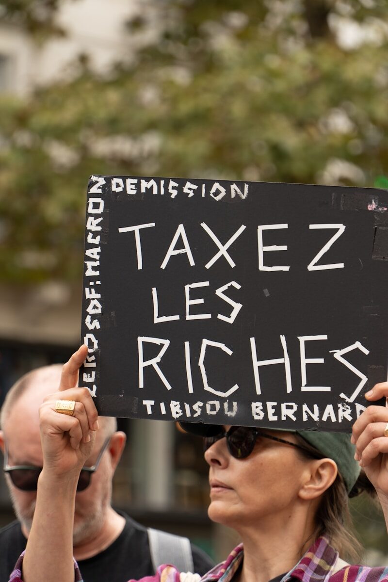 Protesters hold sign demanding to tax the rich