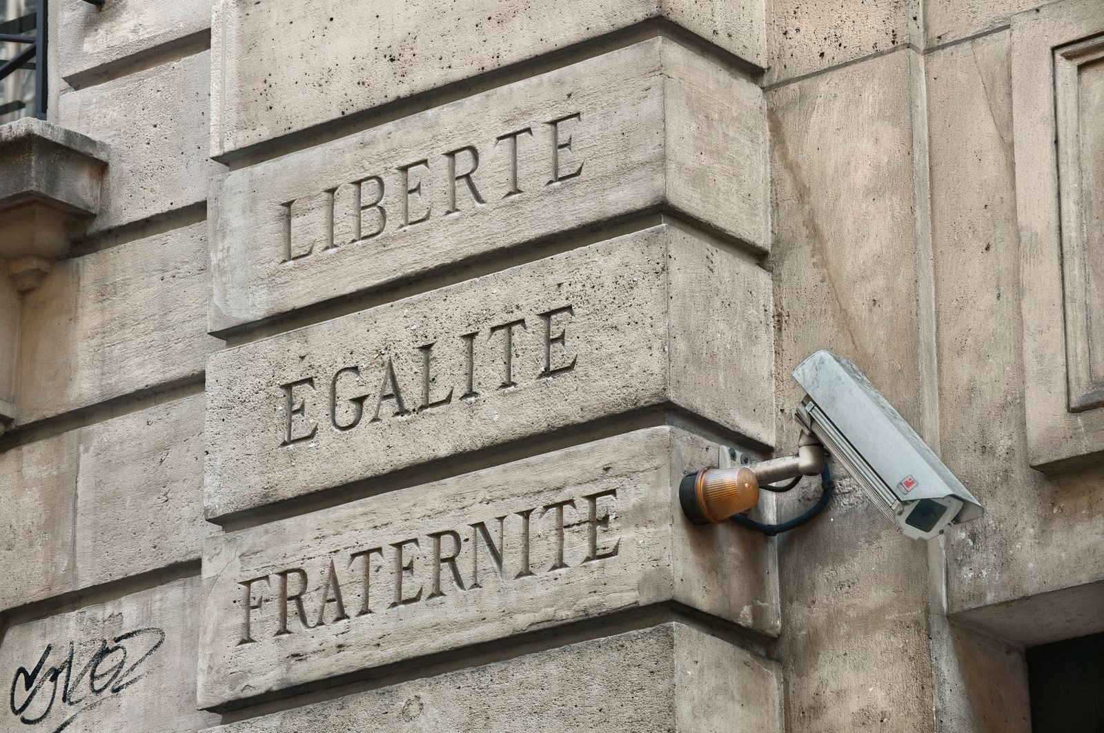 A Parisian wall with 'Liberté, Égalité, Fraternité' and security camera.